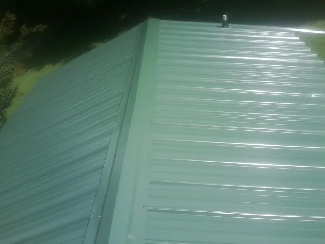New green metal panels meeting at the ridge of a roof — Flat Roof Repair work by our crew in Millbrae