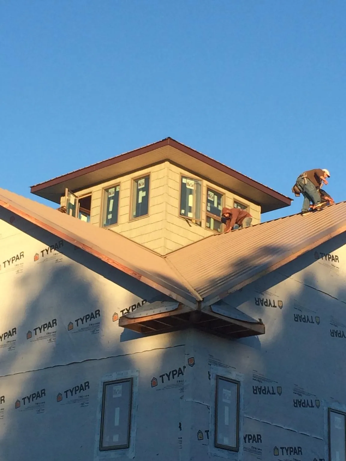 Roofers working around a rooftop cupola on a new metal roof at sunset — Roof Waterproofing in Millbrae by Roofing Brothers